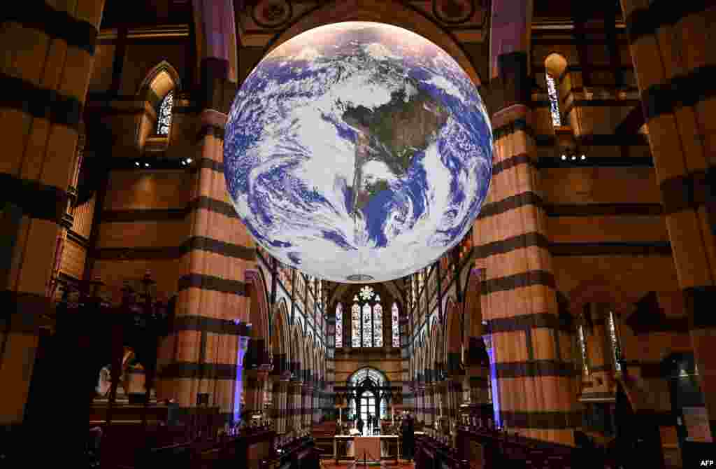 People look at a large globe of the world measuring seven meters in diameter. The artwork is called &quot;Gaia,&quot; by artist Luke Jerram. The globe is suspended and rotates from the ceiling of St Paul&#39;s Cathedral in Melbourne, Australia.