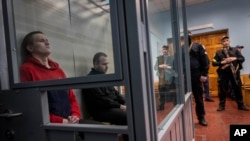 Russian soldiers Alexander Ivanov, right, and Alexander Bobikin sit in a glass box at their trial in Kotelva, northeastern Ukraine, May 26, 2022.