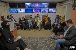 Reporters for TOLOnews cover their faces with masks as they attend an editorial meeting at the TOLOnews TV station in Kabul, Afghanistan, May 22, 2022.