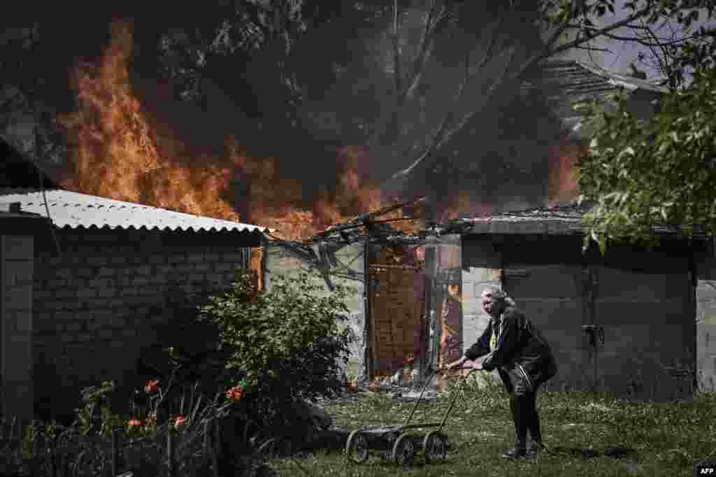 An elderly woman walks away from a burning garage after shelling in the city of Lysytsansk at the eastern Ukrainian region of Donbas, May 30, 2022, on the 96th day of the Russian invasion of Ukraine.