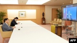 하야시 요시마사(왼쪽) 일본 외무상이 18일 도쿄에서 왕이(화면) 중국 외교담당 국무위원 겸 외교부장과 화상 회담하고 있다.