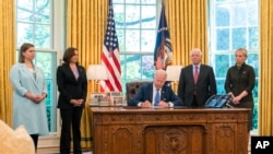 El presidente Joe Biden, acompañado de la vicepresidenta Kamala Harris y tres legisladores más, firma la Ley de Préstamo y Arriendo para la Defensa de la Democracia de Ucrania de 2022 en la Oficina Oval de la Casa Blanca, el 9 de mayo de 2022, en Washington DC.