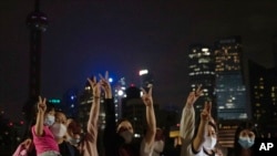 Residents cheer as they pose photos as it nears midnight on the eve of the lifting of a COVID-19 lockdown, May 31, 2022, in Shanghai. Shanghai authorities say they will take major steps Wednesday toward reopening China's largest city after a two-month COVID-19 lockdown that has set back the national economy and largely confined millions of people to their homes.