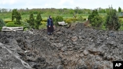 Orthodox Sister Evdokia looks at a crater left after Russian shelling near Slovyansk, Donetsk region, Ukraine, May 10, 2022. The same day, the U.S. House of Representatives approved more than $40 billion in military and humanitarian aid for Ukraine. 
