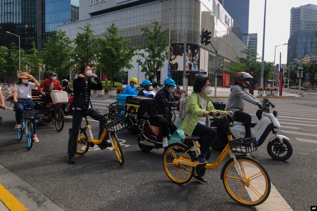 上海市民和快递小哥骑着车在街头等交通灯。（2022年5月31日）(photo:VOA)