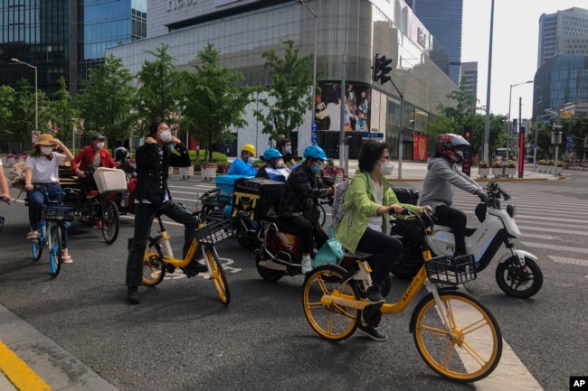 上海市民和快递小哥骑着车在街头等交通灯。(2022年5月31日)