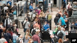 FILE - Travelers queue up move through the north security checkpoint in the main terminal of Denver International Airport, May 26, 2022, in Denver. 