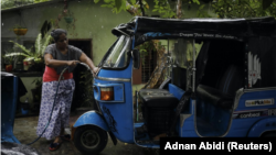 Lasanda Deepthi, 43, an auto-rickshaw driver for local ride hailing app PickMe, cleans her auto-rickshaw in Gonapola town, on the outskirts of Colombo, Sri Lanka, May 23, 2022. (REUTERS/Adnan Abidi)