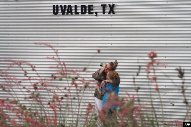 Seorang perempuan menangis dan memeluk seorang gadis saat menelepon di luar Willie de Leon Civic Center Uvalde, Texas, pada 24 Mei 2022. (Foto: AFP)