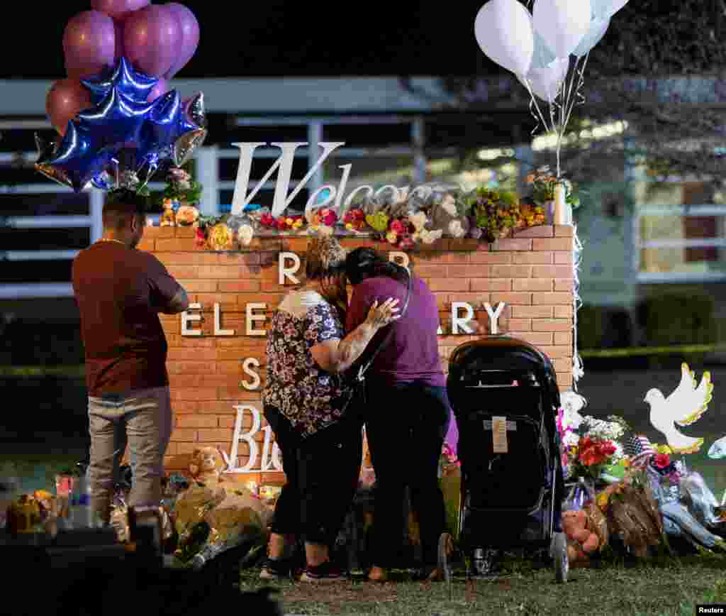 Warga setempat memanjatkan doa di sebuah monumen yang didirikan di luar Sekolah Dasar Robb, lokasi penembakan massal yang menewaskan 19 pelajar dan dua guru, di Uvalde, Texas. (Foto: Reuters)