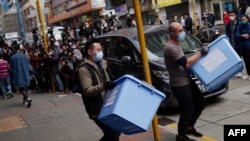 2021年12月29日，一名香港國家安全警察和一名工人從香港《立場新聞》辦公室攜帶出一箱箱證據。（法新社照片）