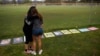 FILE - Two women embrace as they look at signs made by family and friends of people who died from fentanyl-laced pills, including one of their friend, at a makeshift memorial in Santa Monica, California, June 4, 2021.