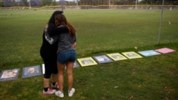 FILE - Two women embrace as they look at signs made by family and friends of people who died from fentanyl-laced pills, including one of their friend, at a makeshift memorial in Santa Monica, California, June 4, 2021.