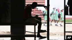 FILE - A man checks his mobile phone in Harare, Zimbabwe, Nov. 29, 2021.