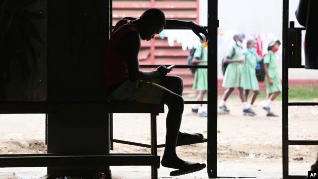 FILE - A man checks his mobile phone in Harare, Zimbabwe, Nov. 29, 2021.