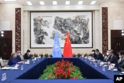 In this photo released by Xinhua News Agency, Chinese Foreign Minister Wang Yi, second right, meets with the United Nations High Commissioner for Human Rights Michelle Bachelet, left, in Guangzhou, in southern China's Guangdong province, May 23, 2022.