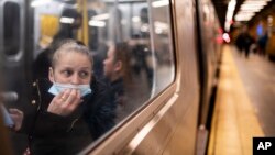 FILE - A passenger looks out onto the platform while riding a northbound train in the 36th Street subway station during the morning commute, in New York, April 13, 2022. 