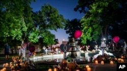 Candles are lit at dawn at a memorial site in the town square for the victims killed in this week's elementary school shooting, May 27, 2022, in Uvalde, Texas.