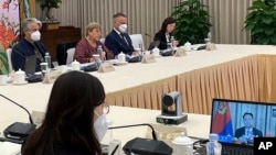 In this photo released by the United Nations, U.N. High Commissioner for Human Rights Michelle Bachelet, second from left, holds a virtual meeting with Vice Minister Du Hangwei of China's Ministry of Public Security, on screen at right, on May 24, 2022.