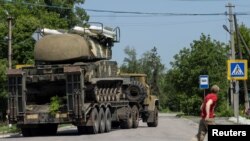 A local resident looks at a rocket launcher vehicle being transported, that's used by Ukrainian forces, amid Russia's invasion of Ukraine, near Kramatorsk, Donetsk region, May 30, 2022