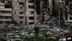 Seorang prajurit Ukraina berjalan di tengah puing-puing sebuah bangunan yang rusak berat oleh beberapa pemboman Rusia di dekat garis depan di Kharkiv, Ukraina, 25 April 2022. (Foto: AP)