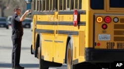 A police officer talks to a school bus driver in Gardena, Calif., Tuesday, Jan. 18, 2011 (AP Photo/Jae C. Hong)