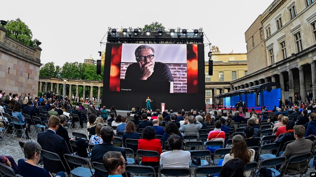 FILE - Spectators attend the award ceremony at the 71st Berlinale Summer Festival at the open-air cinema Museum Island. A photo of Mohammad Rasoulof of Iran, a member of the 2021 International Jury, can be seen on the big screen in Berlin, Germany, June 1