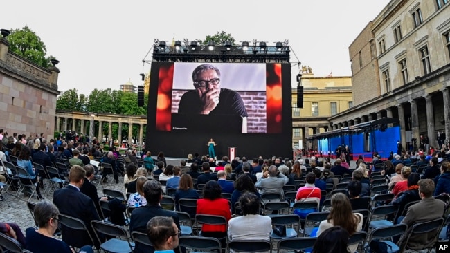 FILE - Spectators attend the award ceremony at the 71st Berlinale Summer Festival at the open-air cinema Museum Island. A photo of Mohammad Rasoulof of Iran, a member of the 2021 International Jury, can be seen on the big screen in Berlin, Germany, June 1