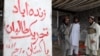 FILE - Armed militants of Tehrik-i-Taliban Pakistan (TTP), stand next to graffiti which reads "Long Live Tehrik-i-Taliban Pakistan," at a camp in a Pakistani tribal district of Mohmand Agency, July 21, 2008. 
