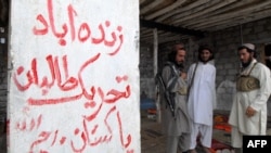 FILE - Armed militants of Tehreek-e-Taliban Pakistan (TTP), stand next to graffiti supporting the group at a camp in a Pakistan, July 21, 2008. Pakistan's army chief on Dec. 13, 2023, asked the U.S. for help in defeating such militant groups, allegedly harboring in Afghanistan.