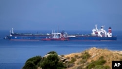 The Pegas tanker, that has recently changed its name to Lana, foreground, is seen off the port of Karystos on the Aegean Sea island of Evia, Greece, May 27, 2022. Greece’s armed forces are on high alert in the Eastern Aegean Sea as tensions escalate with Turkey.