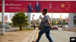 FILE - A woman crosses the street near a billboard commemorating the state visit of Chinese President Xi Jinping in Port Moresby, Papua New Guinea, Nov. 15, 2018. China wants 10 small Pacific nations to endorse a sweeping agreement covering everything fro