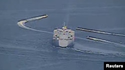 FILE - Three Iranian Revolutionary Guard vessels, some of several to maneuver in what the U.S. Navy said were "unsafe and unprofessional actions against U.S. military ships," are seen next to expeditionary mobile sea base USS Lewis B. Puller in a still image from video taken in the Persian Gulf, April 15, 2020. (U.S. Navy/Reuters)