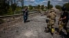 Soldiers of the Kraken Ukrainian special forces unit check a man's documents at a destroyed bridge on the road near the village of Rus'ka Lozova, north of Kharkiv, on May 16, 2022.