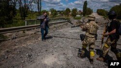 Soldiers of the Kraken Ukrainian special forces unit check a man's documents at a destroyed bridge on the road near the village of Rus'ka Lozova, north of Kharkiv, on May 16, 2022.