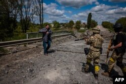 Soldiers of the Kraken Ukrainian special forces unit check a man's documents at a destroyed bridge on the road near the village of Rus'ka Lozova, north of Kharkiv, on May 16, 2022. (Photo by Dimitar DILKOFF / AFP)