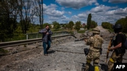 Soldiers of the Kraken Ukrainian special forces unit check a man's documents at a destroyed bridge on the road near the village of Rus'ka Lozova, north of Kharkiv, on May 16, 2022.