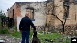 Eduard Zelenskyy pets his dog at his home destroyed by attacks in Potashnya, on the outskirts of Kyiv, Ukraine, on May 31, 2022. Zelenskyy just returned to his hometown after escaping war to find out he is homeless. 