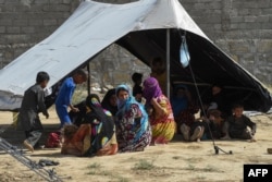 FILE - Afghan refugees sit around a makeshift tent shelter on the outskirts of Quetta, Pakistan, Sept. 6, 2021.