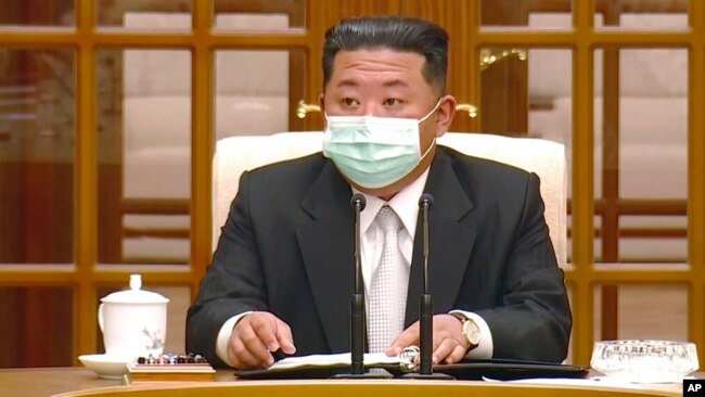 In this image made from video broadcast by North Korea's KRT, North Korean leader Kim Jong Un wears a face mask on state television during a meeting acknowledging the country's first case of COVID-19, May 12, 2022, in Pyongyang, North Korea.