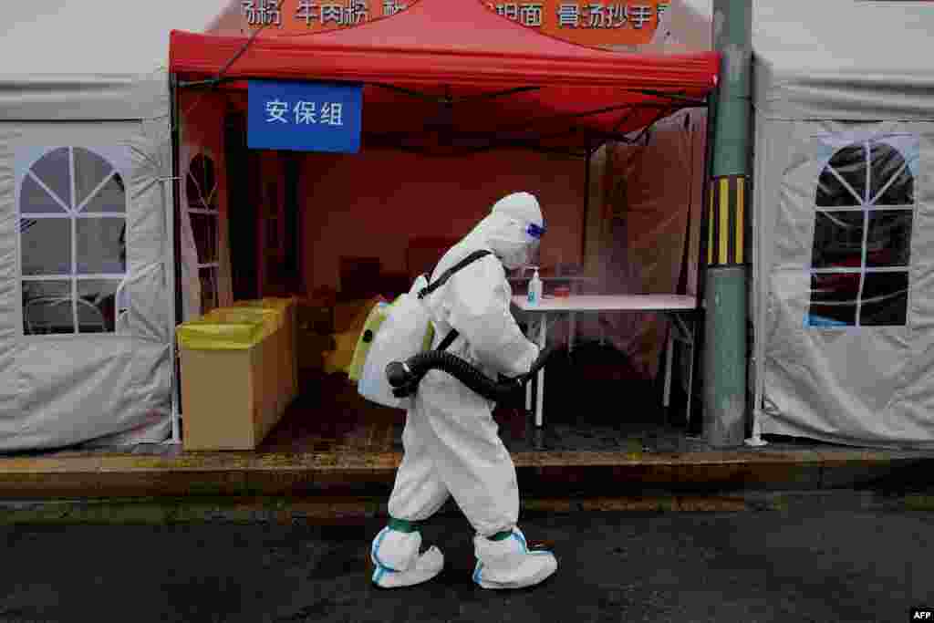A worker wearing personal protective equipment disinfects the entrance to a neighborhood area on lockdown due to the recent COVID-19 outbreaks in Beijing.