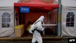 A worker wearing personal protective equipment disinfects the entrance to a residential area on lockdown due to the recent COVID-19 outbreaks in Beijing.