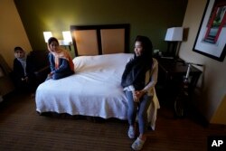 Gulsom Esmaelzade, 35, right, sits with her sisters, Shoriya Esmaelzade, 34, left, and Susan Esmaelzade, 28, in a hotel room where Susan sleeps, May 4, 2022, in San Diego. The family has been shuttled among hotel rooms in the San Diego area since January.