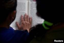 Jaqueline and a fellow inmate read a book in prison where they have access to a small library as part of a program that aims to spread literacy and offer the chance to get out of jail earlier, in La Paz, Bolivia April 29, 2022. (REUTERS/Claudia Morales)