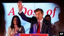 Mehmet Oz, a Republican candidate for U.S. Senate in Pennsylvania, right, waves in front of his wife, Lisa, while speaking at a primary night election gathering in Newtown, Pa., May 17, 2022. 