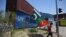 A supporter of Pakistan's Tehreek-e-Insaf (PTI) party carries flags next to containers stacked by authorities to block the Red Zone ahead of a planned rally in support of former Prime Minister Imran Khan, in Islamabad, May 24, 2022.