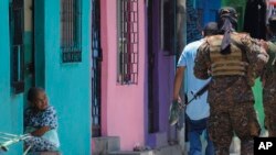 Una anciana observa a soldados que patrullan las calles del barrio San José del Pino en Santa Tecla (El Salvador) el 6 de abril del 2022. Foto AP.