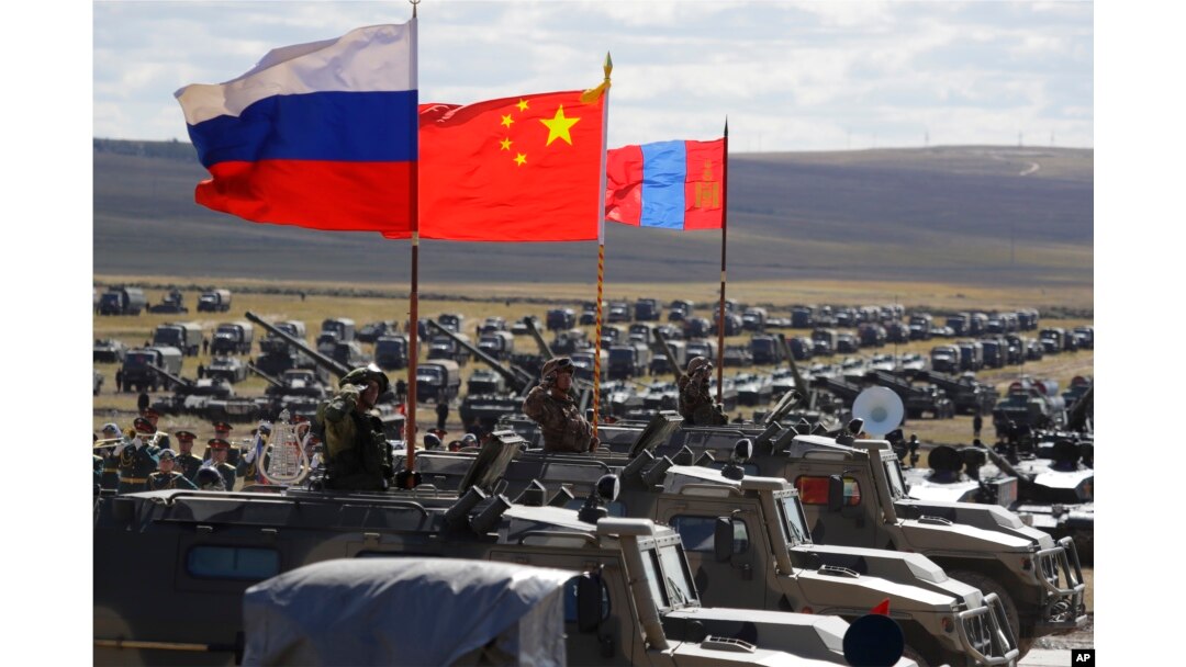 Bendera nasional Rusia, Cina, dan Mongolia yang dipasang pada kendaraan lapis baja berkibar tertiup angin selama latihan militer di tempat latihan "Tsugol", sekitar 250 kilometer tenggara kota Chita selama latihan militer Vostok 2018 di Siberia Timur, Rusia, Kamis , 13 September 2018. (Foto: AP)