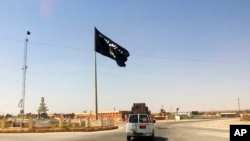 FILE - A motorist passes by a flag of the Islamic State group in central Rawah, 281 kilometers northwest of Baghdad, Iraq, July 22, 2014.