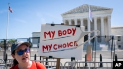 Michelle Peterson, of Silver Spring, Md., protests outside of the Supreme Court, May 10, 2022, which is lined with anti-scaling fencing in Washington.